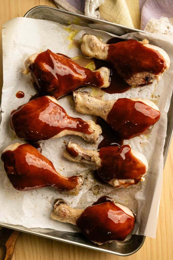 Chicken drumsticks brushed with glossy BBQ sauce before the second bake