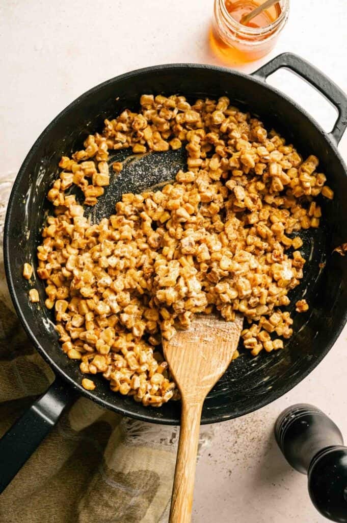 Close-up of skillet corn coated in a creamy honey butter glaze