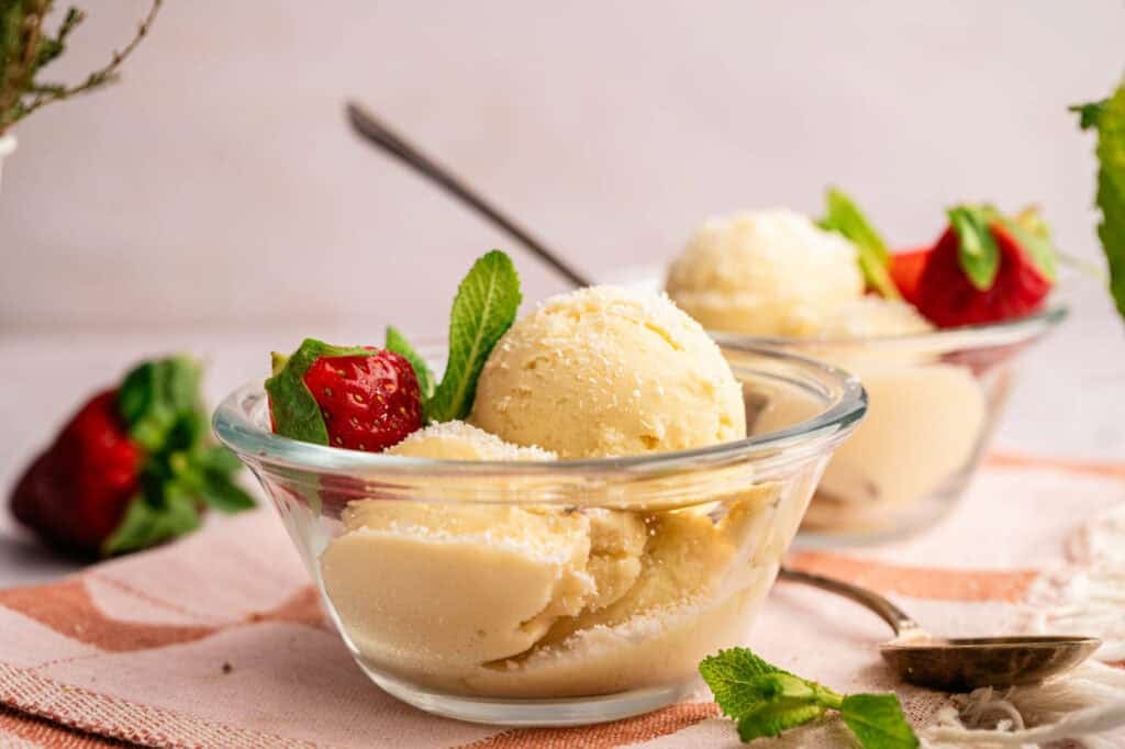 Ninja Creami Dole Whip served with fresh strawberries and mint in glass bowls.