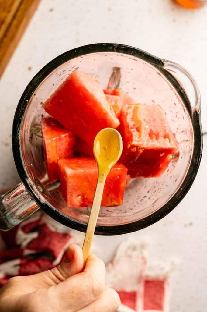 Refreshing chopped watermelon is placed in a blender with a spoon of honey.